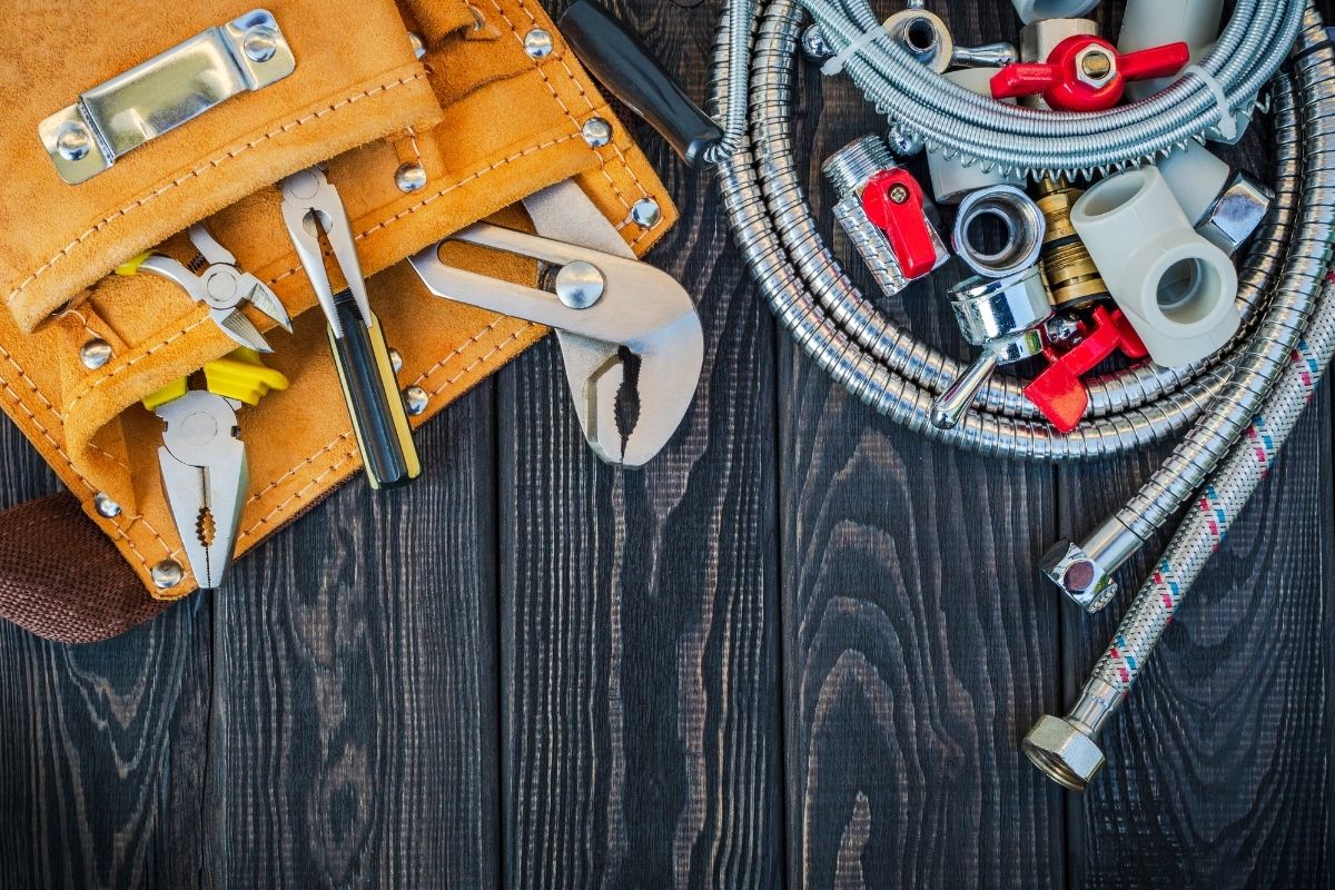 An assortment of hand tools displayed on a wooden table, featuring pliers, hammers, and screwdrivers in a neat arrangement