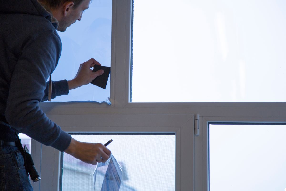A man applying a window sticker to a glass window, focused on ensuring proper placement and alignment.